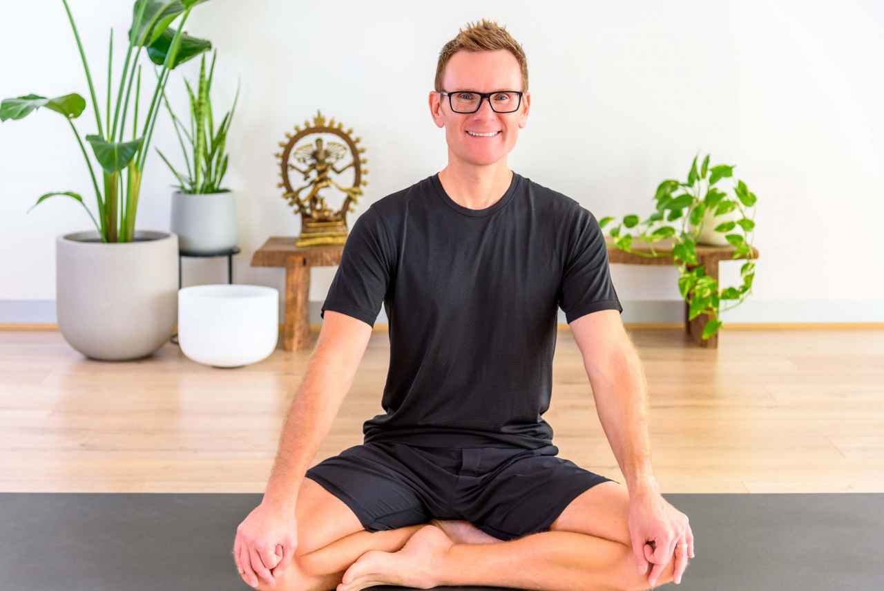 A smiling man performing a yoga pose